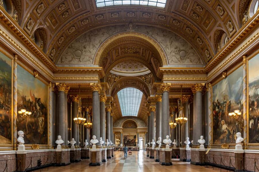 A gilded state room on the Versailles estate, chandeliers lit